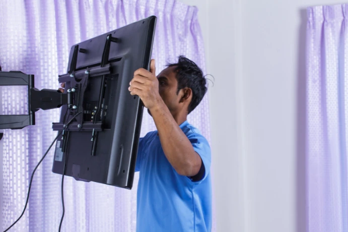 Technician supporting a TV while removing it from a wall mount
